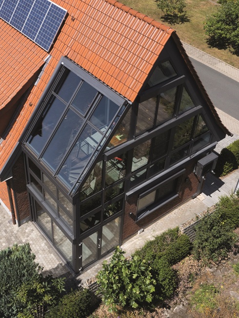 Ein Wintergarten über zwei Etagen, mit verglastem Giebel: Erd- und Obergeschoss sind über eine Wendeltreppe verbunden