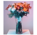Eleganter Strauß gemischter Blumen in einer Glasvase mit sanfter Beleuchtung.