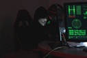 Anonymer Hacker mit einer Maske sitzt an einem Computer