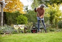 Eine Frau hakt Laub in einem Garten 
