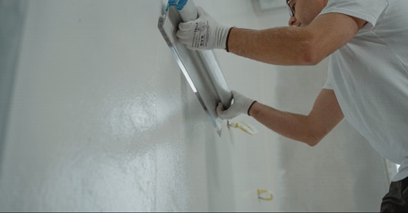 Mann trägt Innenputz auf eine Wand und glättet die Oberfläche bei Renovierungsarbeiten 