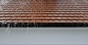 Regenwasser tropft an einer Dachrinne hinab 