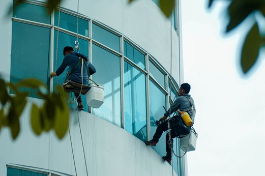 Fensterputzer reinigen die Glasfassade eines Hochhauses.