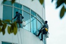 Fensterputzer reinigen die Glasfassade eines Hochhauses.